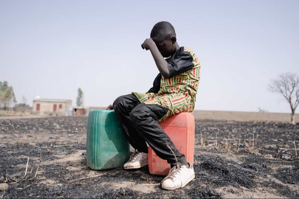 African teenager strained for walking long distance to collect clean water.